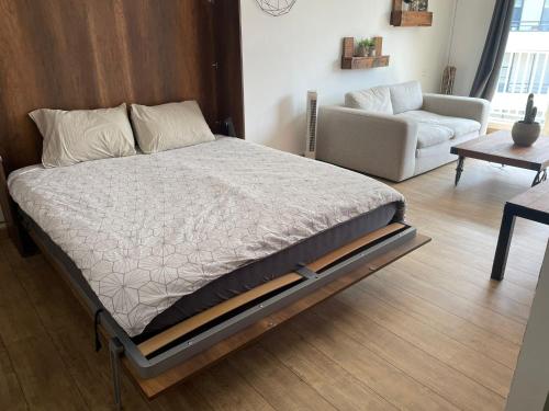 ein großes Bett in einem Zimmer mit Sofa und Tisch in der Unterkunft Studio Rouen in Rouen