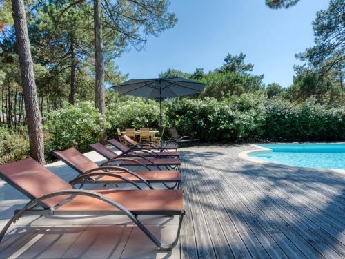 - une rangée de chaises avec un parasol à côté de la piscine dans l'établissement Villa Villa La Lisière des Pins by Interhome, à Lacanau-Océan