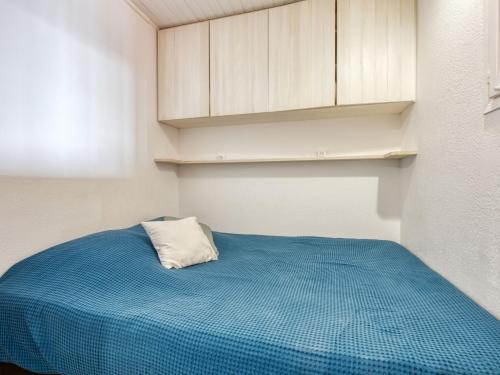 a small bedroom with a blue bed and white cabinets at Apartment Primavéra-8 by Interhome in Lacanau-Océan