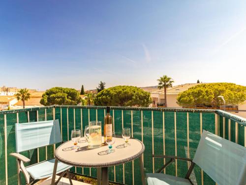 - une table avec des verres à vin et une bouteille sur le balcon dans l'établissement Apartment Les Ilaires by Interhome, au Lavandou