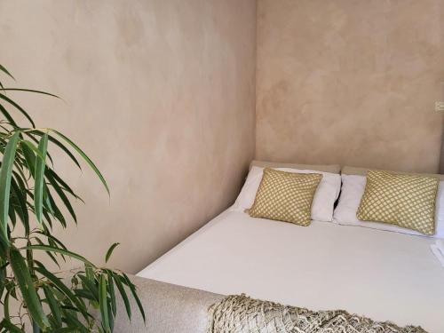 a white bed with two pillows and a plant at Apartments Grgic in Njivice