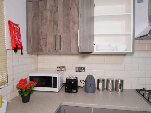 un bancone della cucina con forno a microonde su un piano di lavoro di Cosy & Spacious 4 Bedroom House with Free Parking in Birmingham 