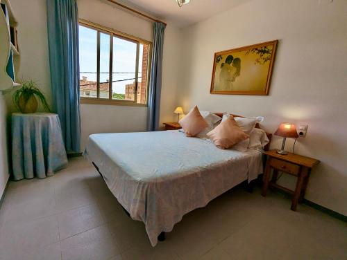 a bedroom with a bed with pillows and a window at Apartamentos El Dorado in Miami Platja