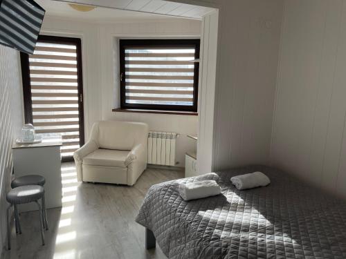 a bedroom with a bed and a chair and a window at Willa Anna in Gródek Nad Dunajcem