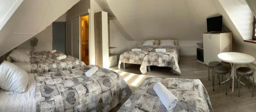 um quarto no sótão com 3 camas e uma mesa em Willa Anna em Gródek Nad Dunajcem