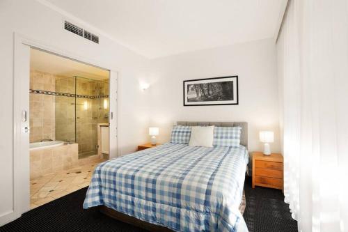 - une chambre avec un lit et une salle de bains pourvue d'une douche dans l'établissement Noosa Beachside Apartment, à Noosa Heads