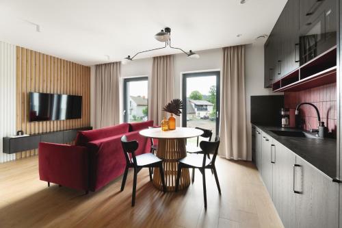 Il comprend une cuisine et un salon avec une table et un canapé rouge. dans l'établissement Apartamenty Na Łąkach, à Kudowa-Zdrój
