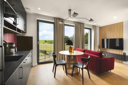 a kitchen and living room with a red couch and a table at Apartamenty Na Łąkach in Kudowa-Zdrój