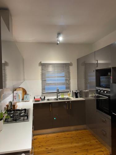a kitchen with a sink and a stove at Charming & Cozy 2BR Cottage in Blacktown