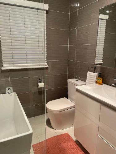 a bathroom with a toilet and a sink and a mirror at Charming & Cozy 2BR Cottage in Blacktown