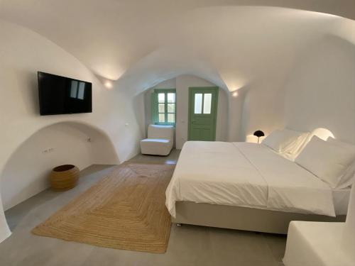 a white bedroom with a bed and a flat screen tv at Sohora Villa in Éxo Goniá