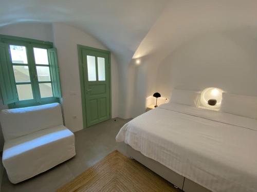 a white bedroom with a bed and a chair at Sohora Villa in Éxo Goniá