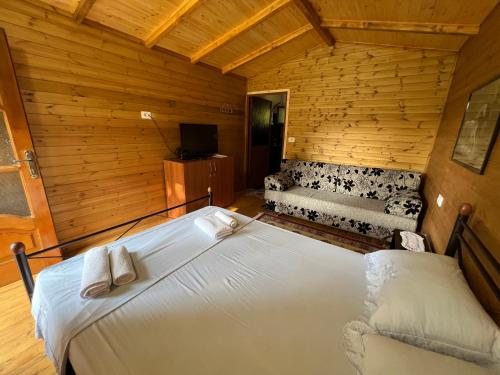 1 dormitorio con 1 cama y 1 sofá en una habitación en Bujtina Llogara, Log Cabins, en Vlorë