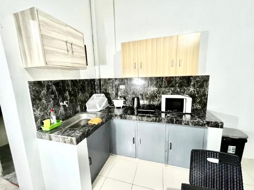 a kitchen with a sink and a microwave at Transient Home at Tierra Vista near SM Dasma with Wifi and Netflix in Mabatang