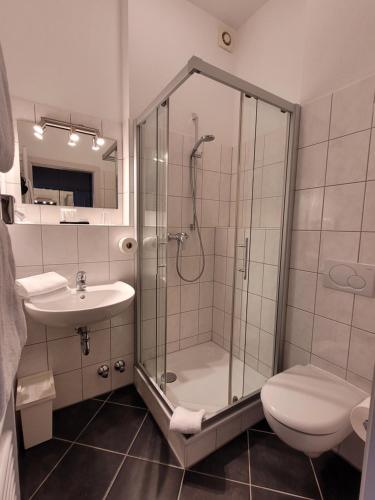a bathroom with a shower and a toilet and a sink at Hotel Rosengarten in Bad Salzuflen