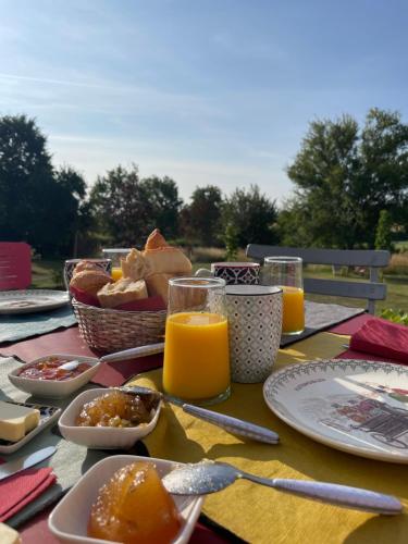 een tafel met borden eten en glazen sinaasappelsap bij Domaine de La Vove in Corbon