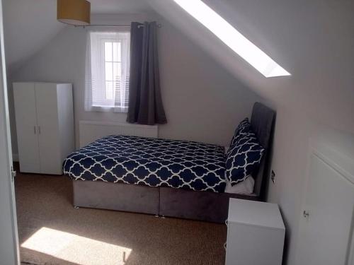 a bedroom with a bed with a blue comforter and a window at Modern Spacious 4 Bed House-with Private Parking in Birmingham 