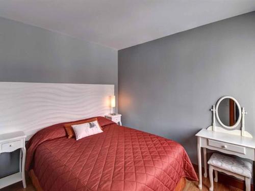 um quarto com uma cama vermelha e um espelho em Bright Condo near the Lake by GLOBALSTAY em Mont-Tremblant