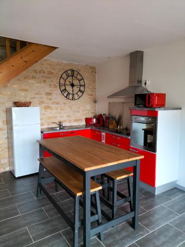 a kitchen with red counters and a wooden table at Domaine de BELLEVUE in Pouançay