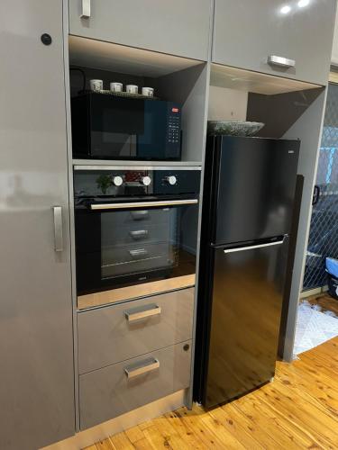 a kitchen with a black refrigerator and a microwave at Charming & Cozy 2BR Cottage in Blacktown