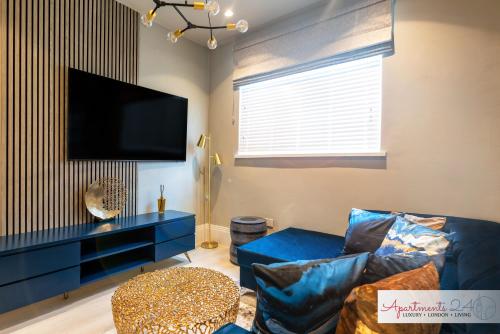 a living room with a blue couch and a flat screen tv at Beautiful Apartment In London in Hounslow