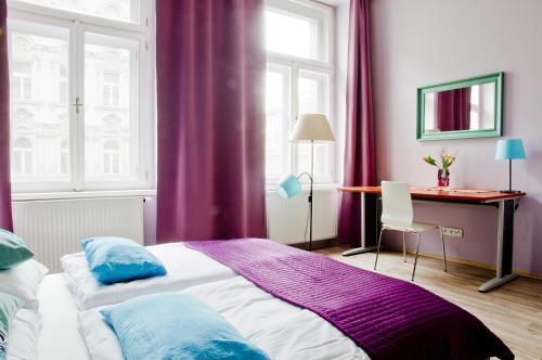 1 dormitorio con cortinas moradas, 1 cama y escritorio en Royal Court Legerova en Praga