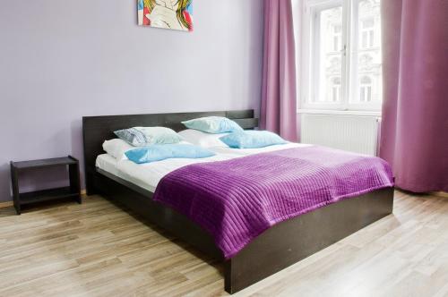 a bedroom with a bed with a purple blanket at Royal Court Legerova in Prague