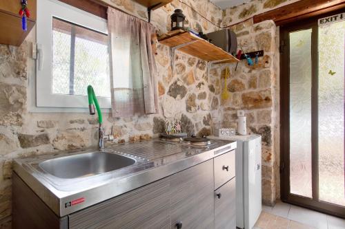 a kitchen with a sink and a stone wall at Lithahiro stone house in Keri
