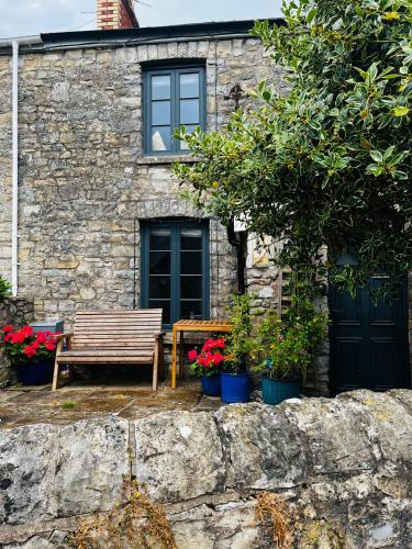 a wooden bench sitting in front of a stone house at Nightingale Cottage in Llantwit Major