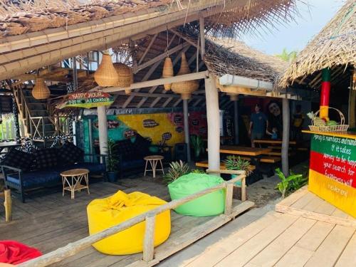 a restaurant with a thatched roof and a wooden deck at Backpack Beach Hostel & Reggae Bar in Galle