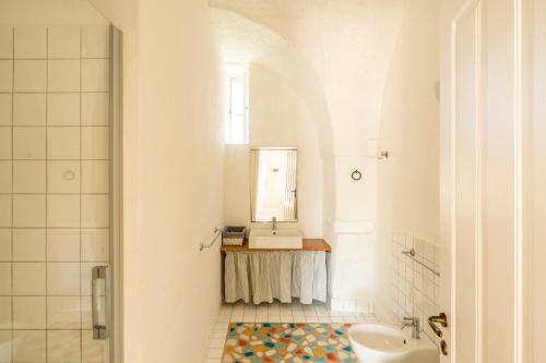a white bathroom with a sink and a mirror at Suite Dimora Storica Maccarone in Fasano