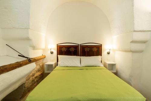 a bedroom with a green bed in a white room at Suite Dimora Storica Maccarone in Fasano