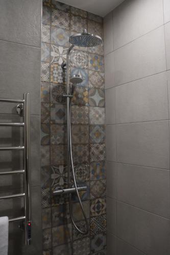 a shower in a bathroom with a tile wall at Orion ApartHotel in Yerevan