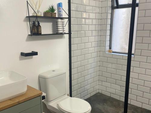 a white bathroom with a toilet and a sink at Lazydaze Point in Jeffreys Bay
