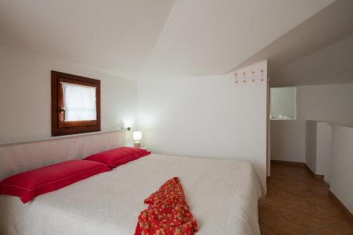 een slaapkamer met een groot wit bed met rode kussens bij Casa Olbiamare by Wonderful Italy in Olbia
