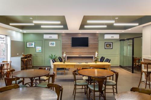 a conference room with tables and chairs and a flat screen tv at Hotel Dom Rafael Premium in Santa Maria