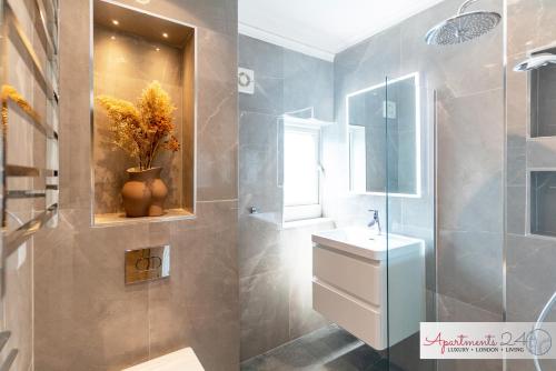 a bathroom with a sink and a shower with a mirror at Beautiful Apartment In London in Hounslow