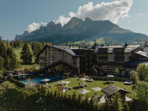 a resort with a large building and a mountain at Hotel Alpenrose in Carezza al Lago