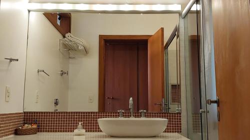 a bathroom with a sink and a large mirror at Pousada Asa do Vento in São Luiz do Paraitinga