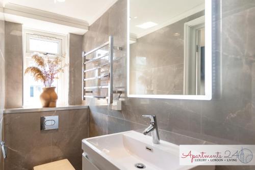 a bathroom with a sink and a mirror at Beautiful Studio Apartment - London in Hounslow