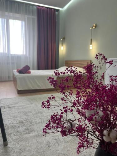 um quarto de hotel com uma cama e flores roxas em Sholpan city studia 118/2 em Almaty