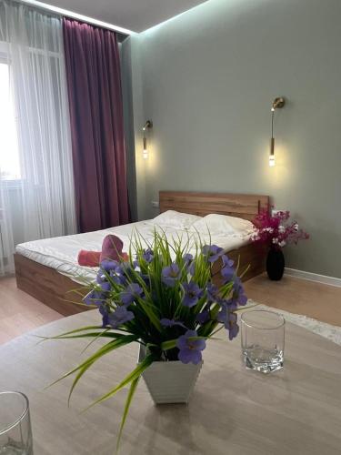um quarto com uma cama e uma mesa com flores em Sholpan city studia 118/2 em Almaty