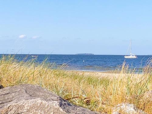 a sandy beach with a sail boat in the water at Ferienanlage Kieferneck in Freest