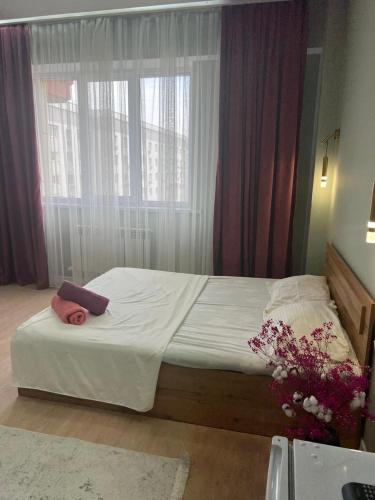 um quarto com uma cama com uma janela e flores em Sholpan city studia 118/2 em Almaty