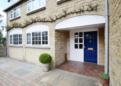 a brick house with a blue door and white garage at Yew Tree House in Woodstock