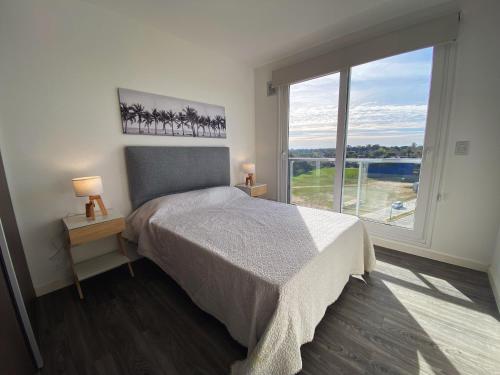 a bedroom with a bed and a large window at Departamentos Premium - Boero Rentals in Belén de Escobar