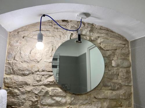 La salle de bains est pourvue d'un miroir suspendu à un mur en pierre. dans l'établissement Altrelli B&B, à Corato