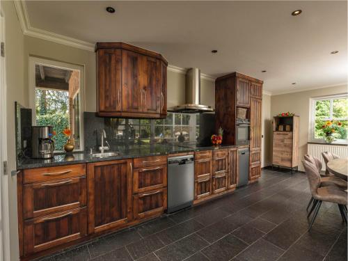 cocina grande con armarios y electrodomésticos de madera en Holiday Home Het Landhuis by Interhome, en Losser