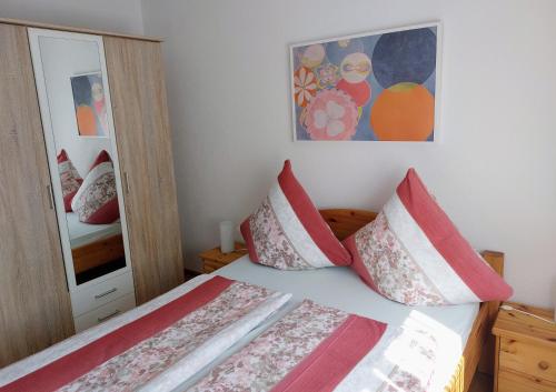 una camera da letto con letto, cuscini e specchio di Appartement - FeWo Wenne a Langenau