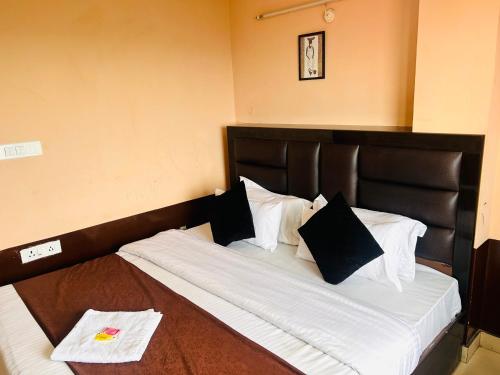 uma cama grande com lençóis brancos e almofadas pretas em HANU VATIKA The FAMILY CHOICE em Shimla